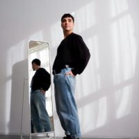Fashionable man in jeans and sweater posing in bright indoor setting, Berlin.