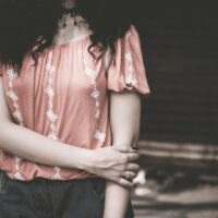 Stylish young woman in casual embroidered top in soft light.