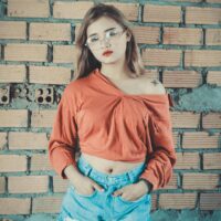 Fashionable woman in casual clothes posing against a brick wall.